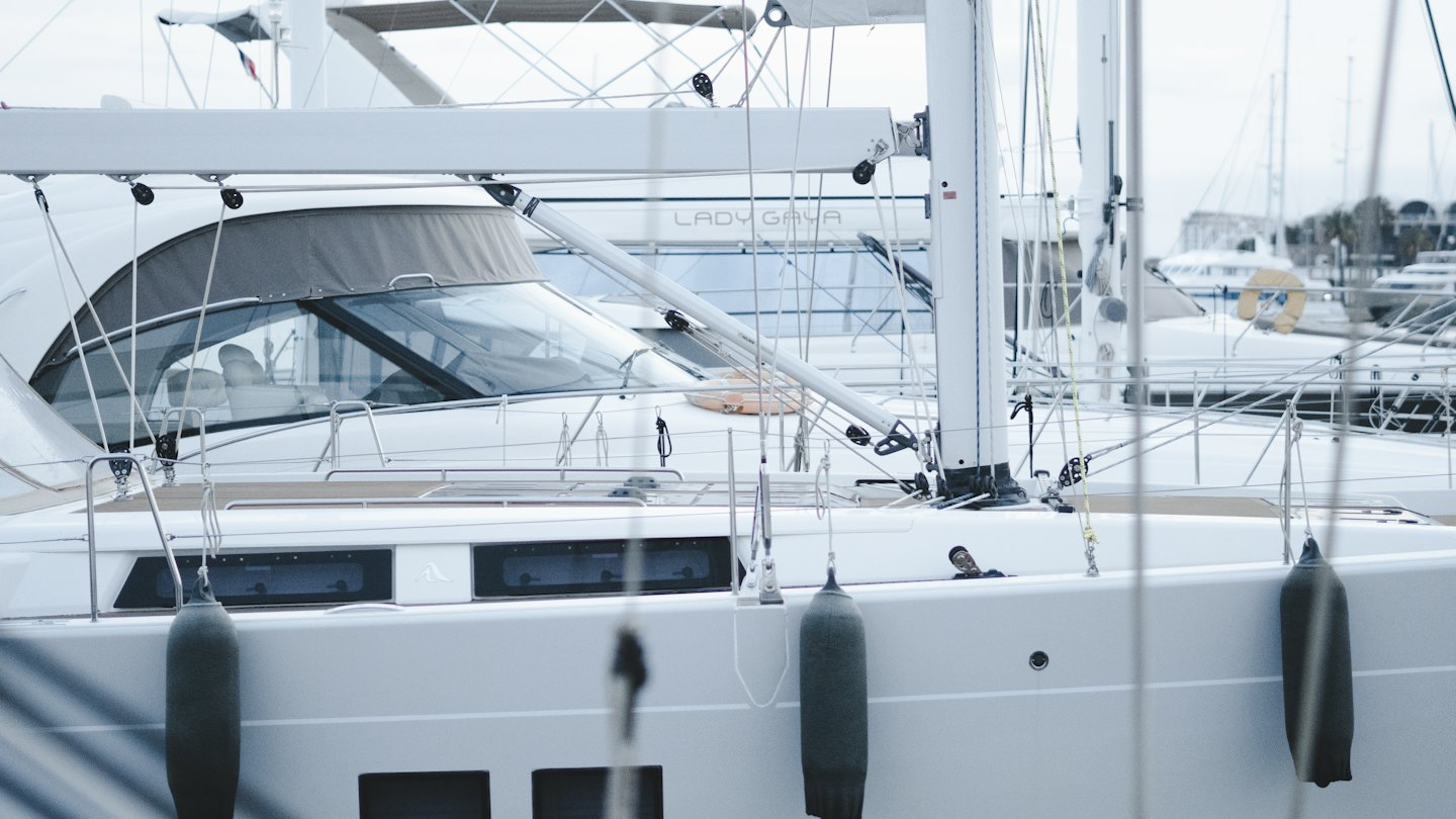 Sailboat hull with hanging fenders moored at a marina.
