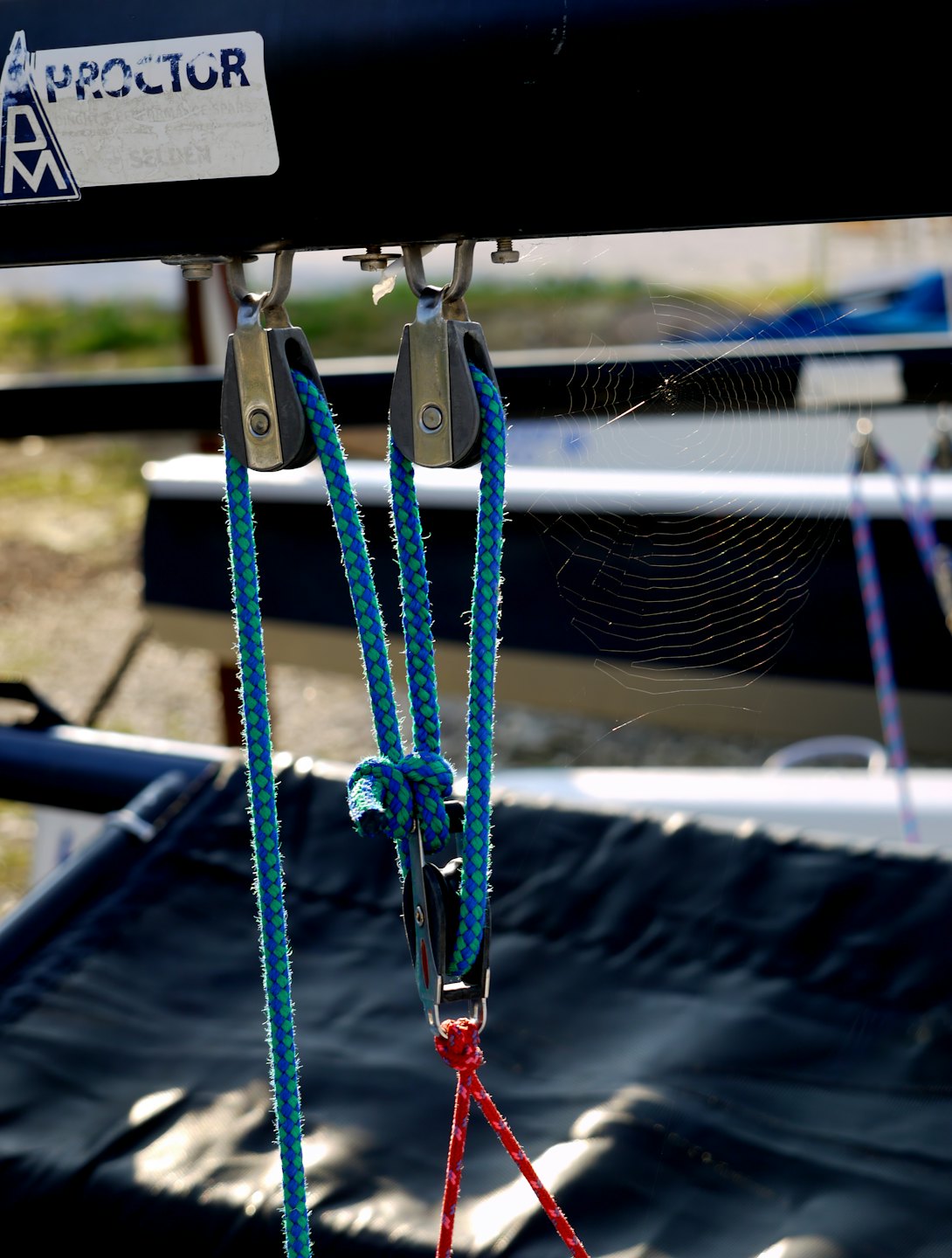 Blue and green ropes thread through pulleys on boat rigging.