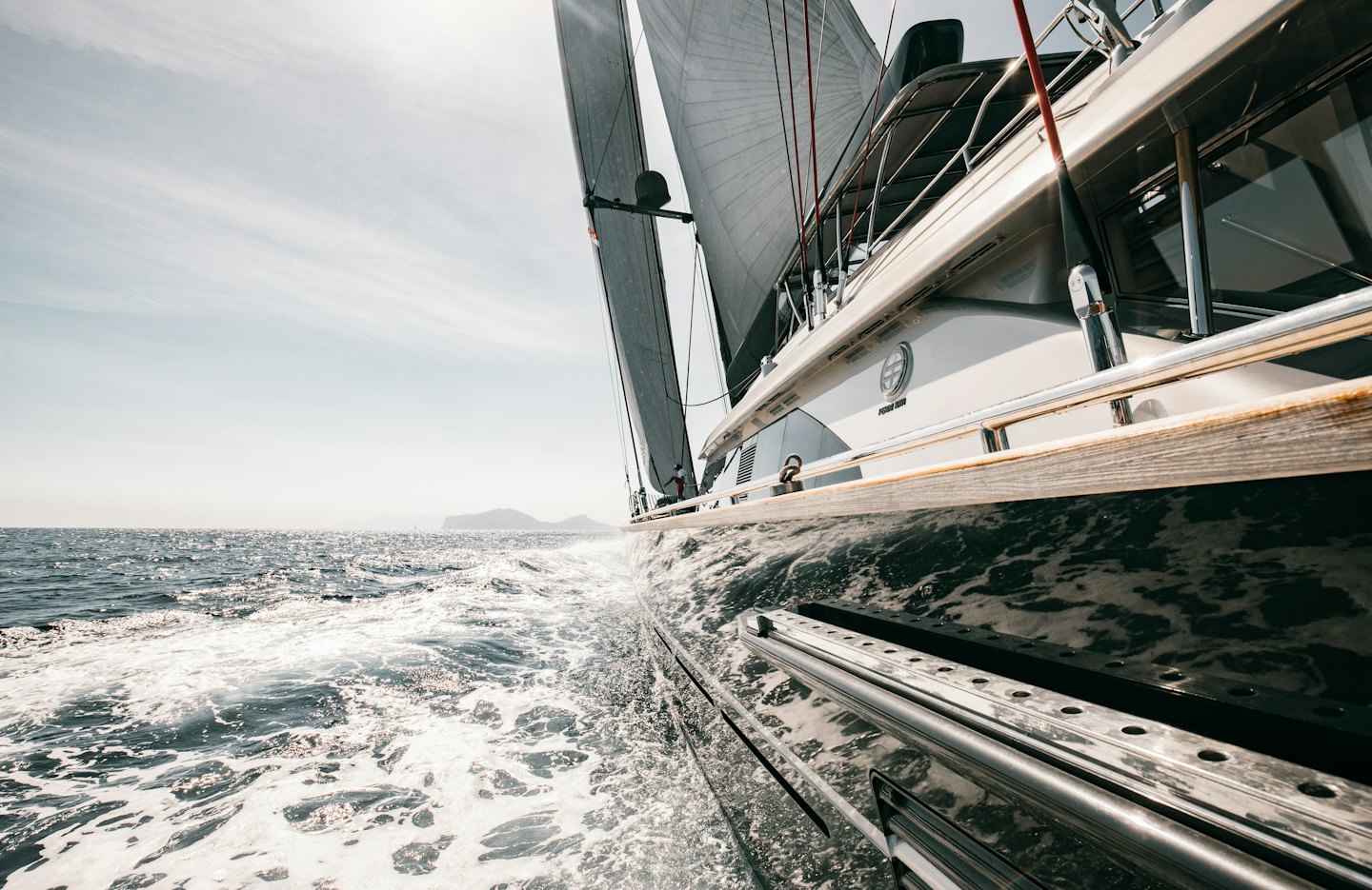 Sleek sailing yacht cutting through sparkling blue water on a clear day.