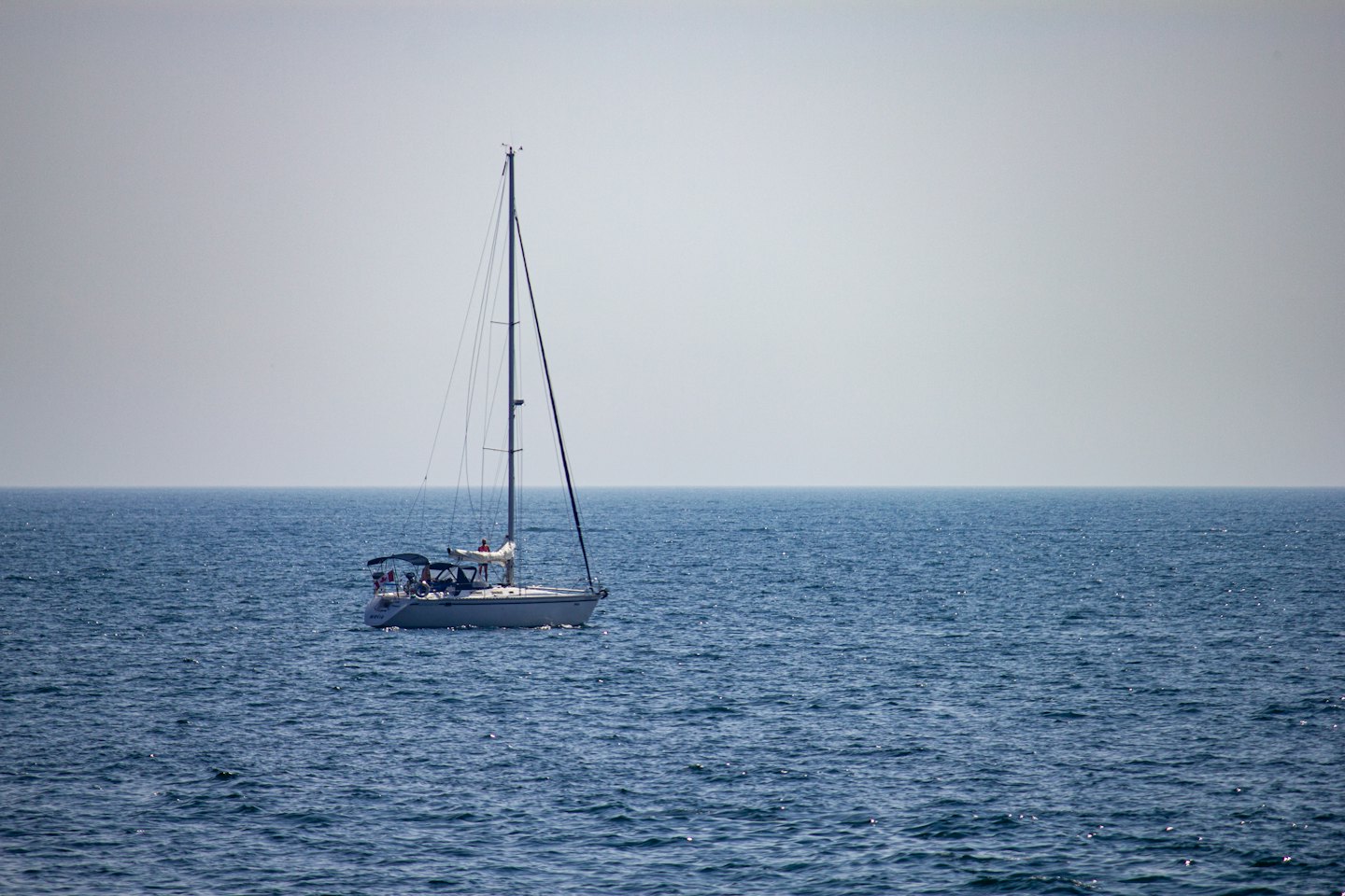 A sailboat with people aboard navigating the open ocean.